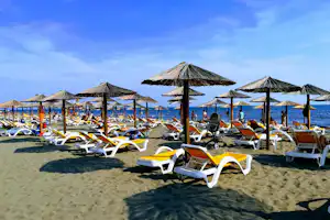 MCM Camping & Resort - Strandbereich vom Campingplatz mit Liegestühlen und Sonnenschirmen