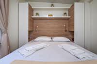 Mediteran Kamp @ Camping Porton Biondi - Schlafzimmer mit einem Doppelbett und Fenster in einer Mietunterkunft