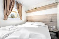 Mediteran Kamp @ Camping Ulika Naturist - Schlafzimmer mit Doppelbett und Fenster zur Veranda in einer Mietunterkunft