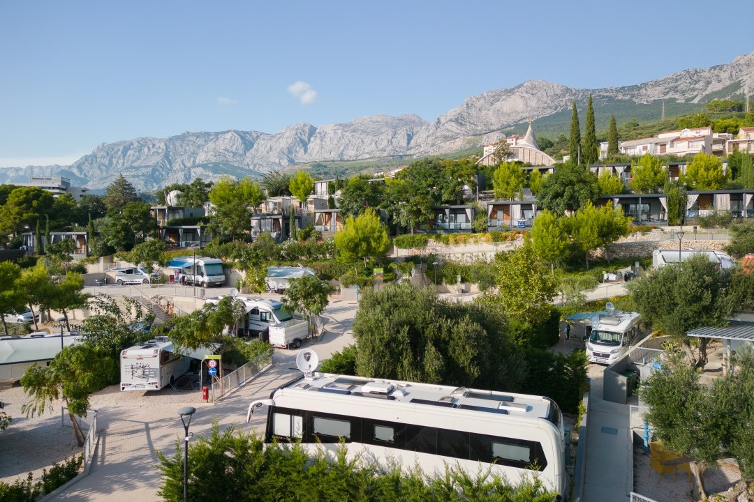 Medora Orbis Camping & Glamping - Blick auf die Standplätze auf dem Campingplatz mit Bergen im Hintergrund