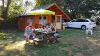 Mini Camping Drentse Monden - Gäste sitzen vor dem Mobilheim im Schatten der Bäume auf dem Campingplatz