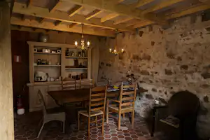 Holzveranda mit Esstisch und Stühlen, Steinvand und offenem Küchenbereich mit Regalen und Geschirr.