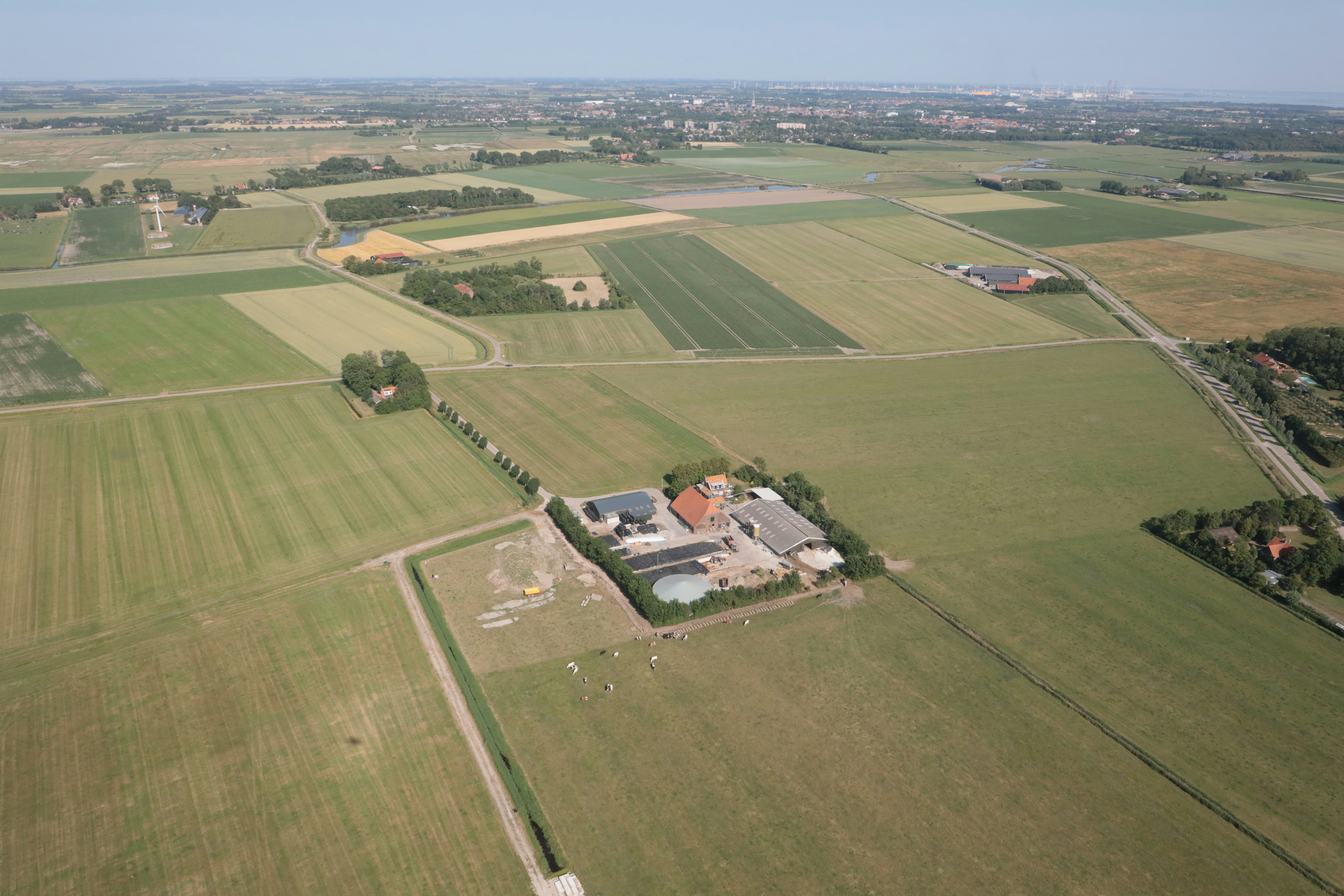 Luftaufnahme eines Campingplatzes mit Gebäuden und Wegen inmitten von Feldern und Wiesen.