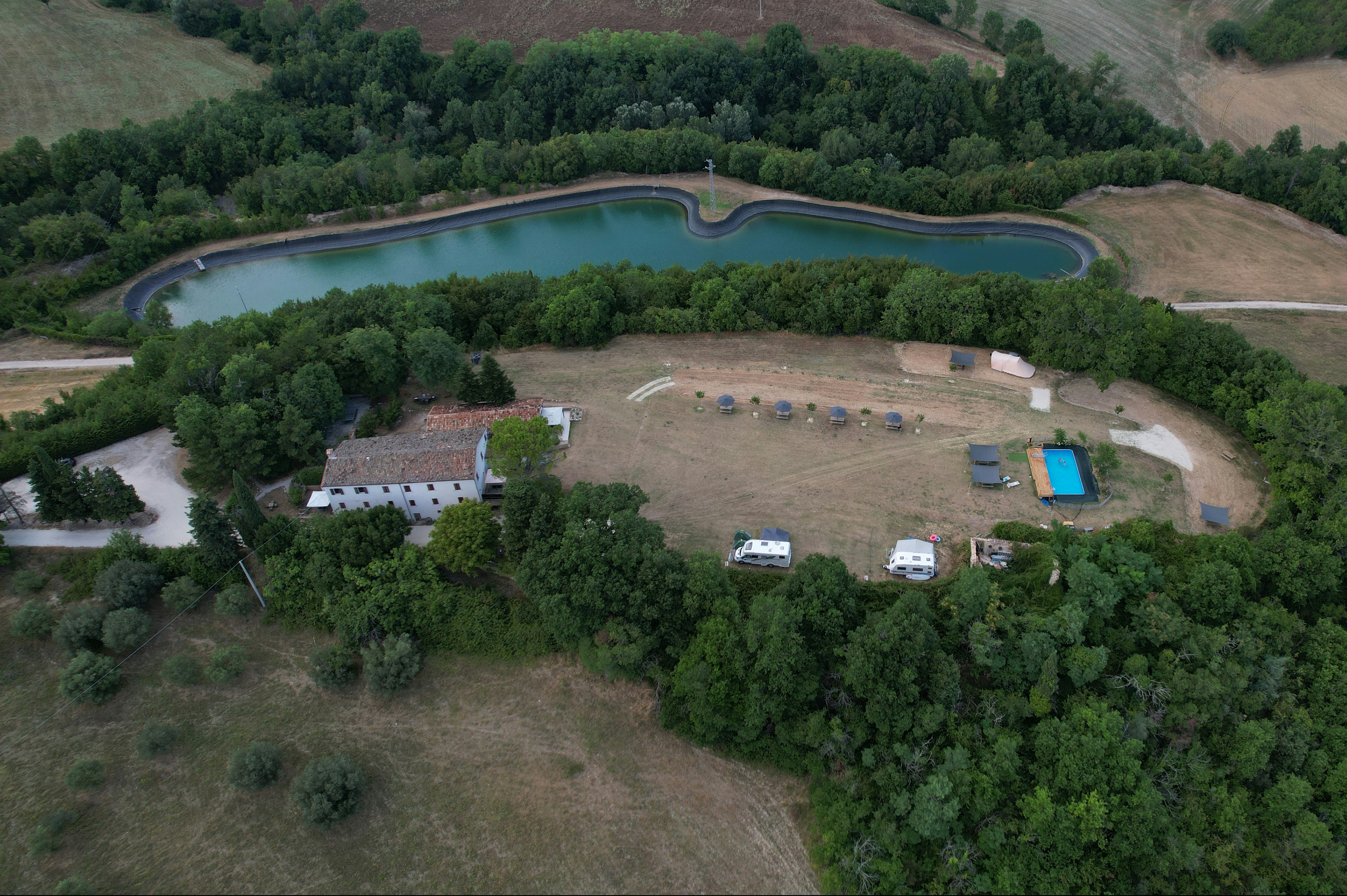 Luftaufnahme eines Campingplatzes am Stausee mit Uferweg, Wohnwagen-Stellplätzen und Wald im Hintergrund.