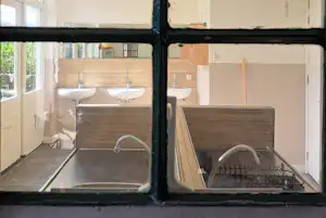 Doppel-Waschbecken im Camping-Badezimmer mit Holzverkleidung, Spiegel und Handtuchhalter, Blick durch einen Rahmen.