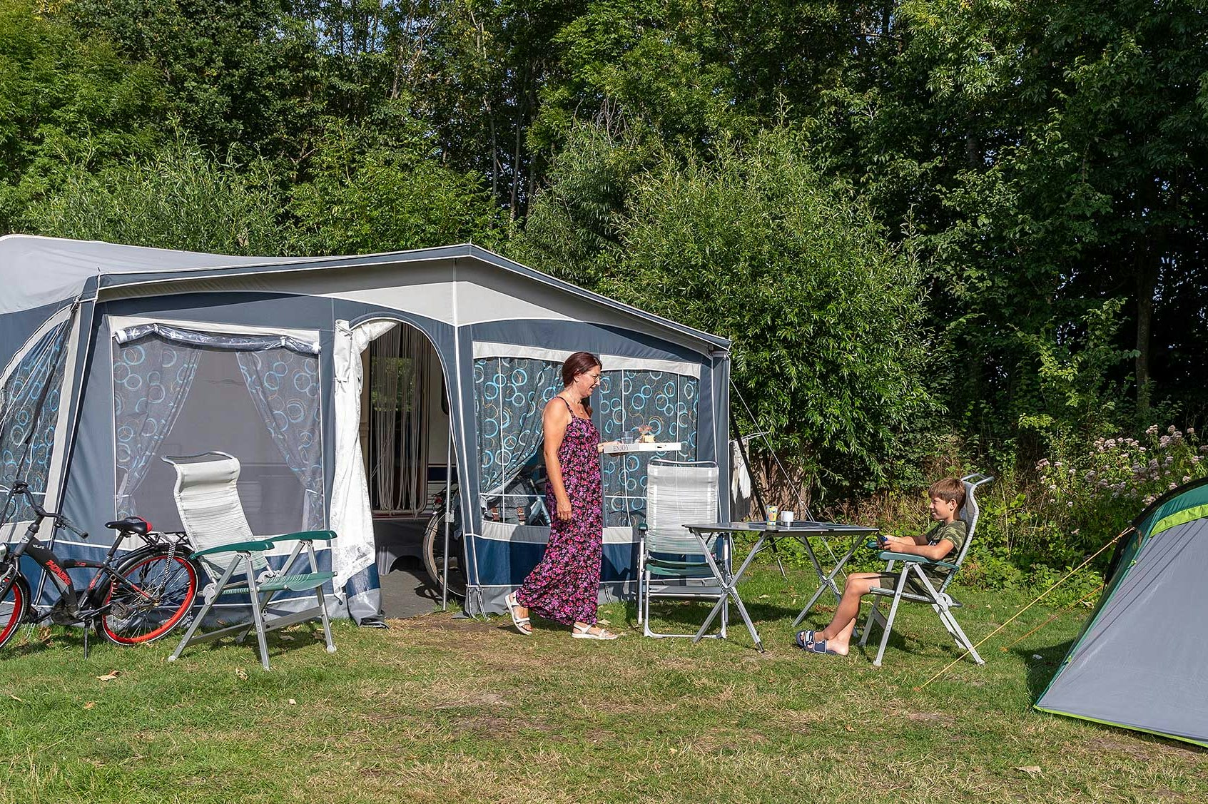 Molecaten Park Rondeweibos - Mutter mit Kind vor ihrem Wohnwagen auf einem Standplatz