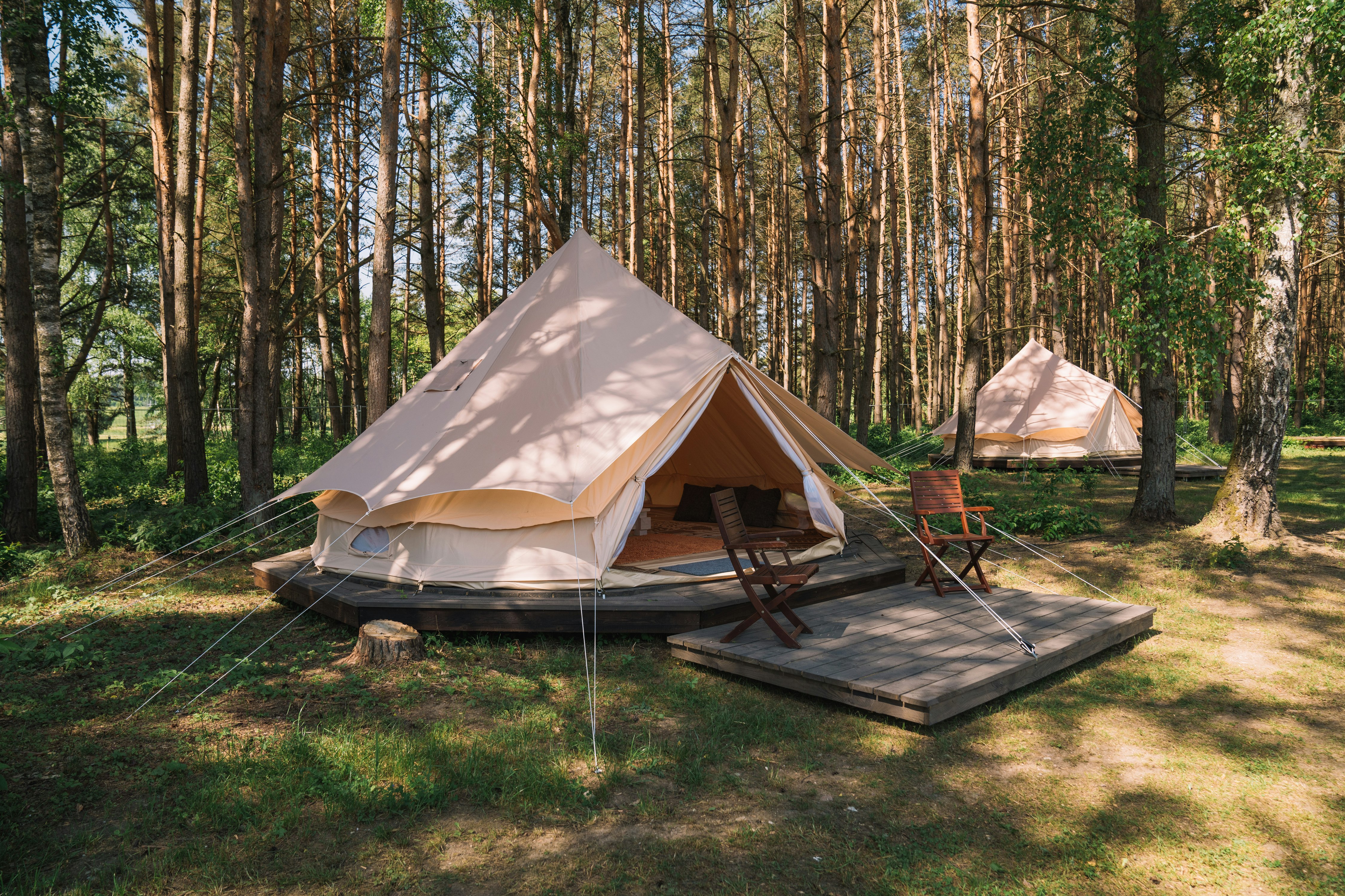Natur Camp Birstonas - Glampingzelte mit Terrasse und Stühlen im Halbschatten zwischen Bäumen