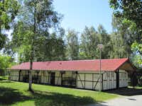 Naturcamp Pruchten - von Bäumen umringtes Fachwerk-Sanitärhaus auf dem Campingplatz