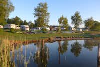 Naturcamping Hellör - Stellplätze im Schatten unter Bäumen mit Kanus am See auf dem Campingplatz