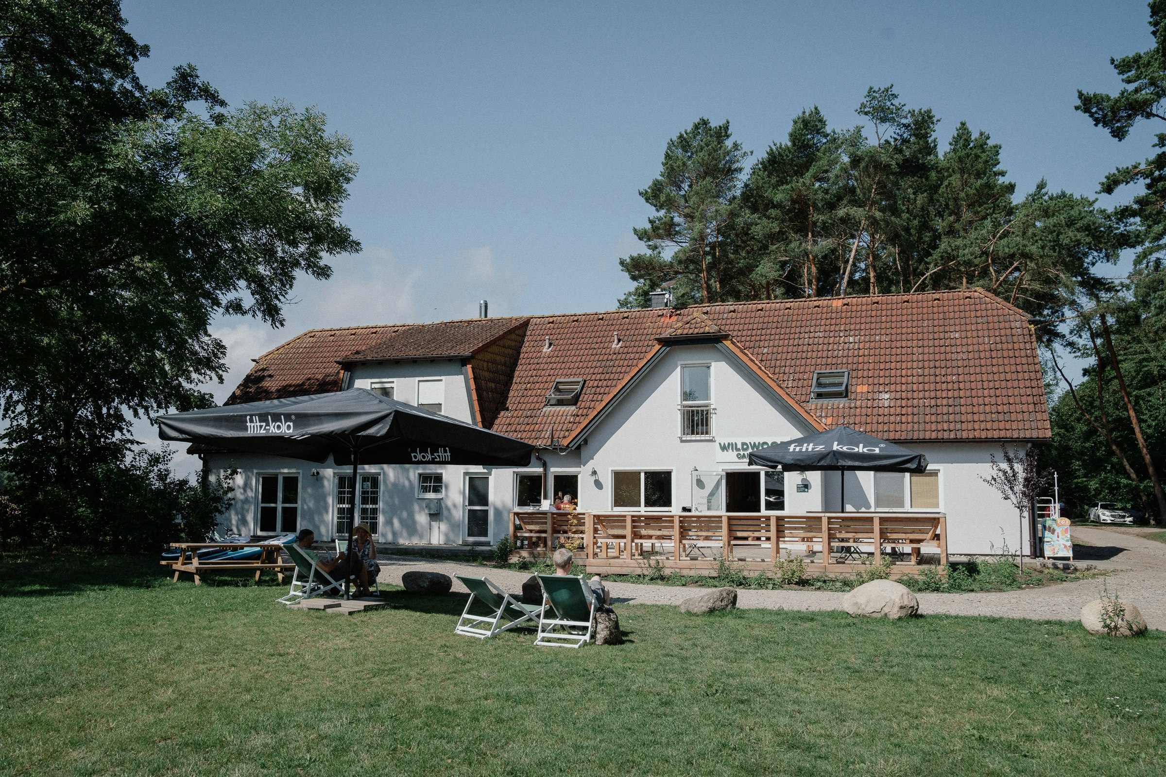 Wildwood Camping Rügen - Außenansicht Clubhouse mit Terrasse und Liegen