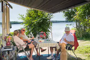 Naturcamping Spitzenort - Gäste vor dem Wohnwagen im Schatten am Plöner See auf dem Campingplatz