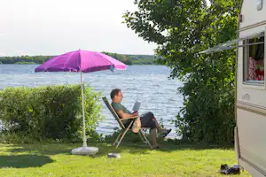 Naturcamping Spitzenort - Gast vor dem Wohnwagen im Schatten am Plöner See