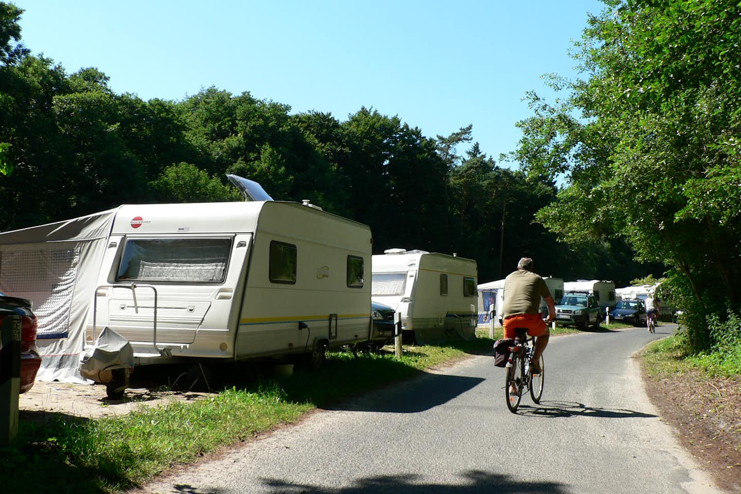Naturcamping Ückeritz  -  Camper mit Fahrrad entlang der Wohnwagen und Wohnmobile auf dem Campingplatz