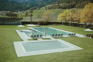 Camping Tisens Naturcaravanpark Tisens - Pool im Freien mit Liegestühlen und Sonnenschirmen