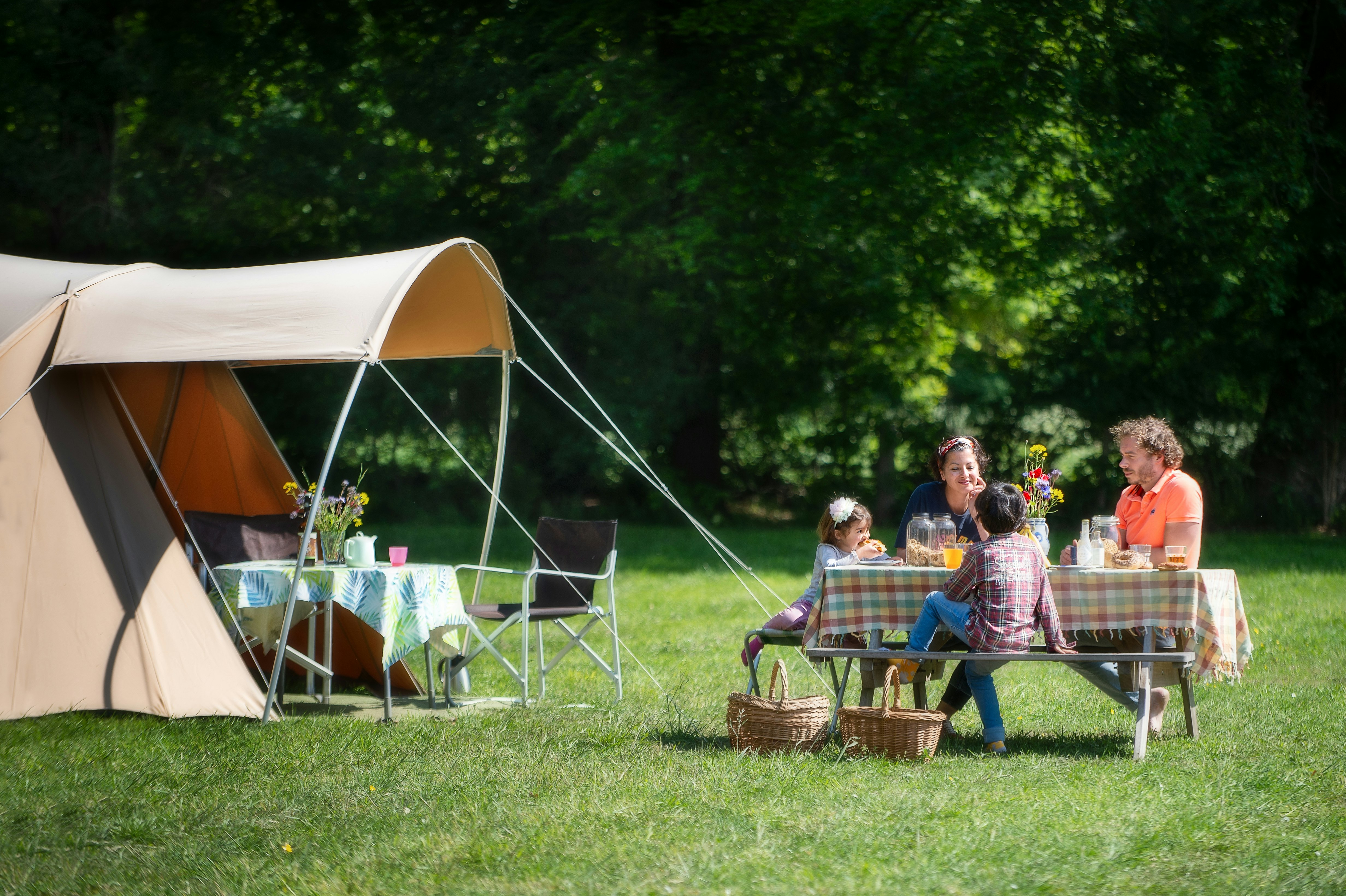 Natuurkampeerterrein Landgoed de Hoevens  - Familie sitzt an einem Picknicktisch vor ihrem Glamping-Zelt