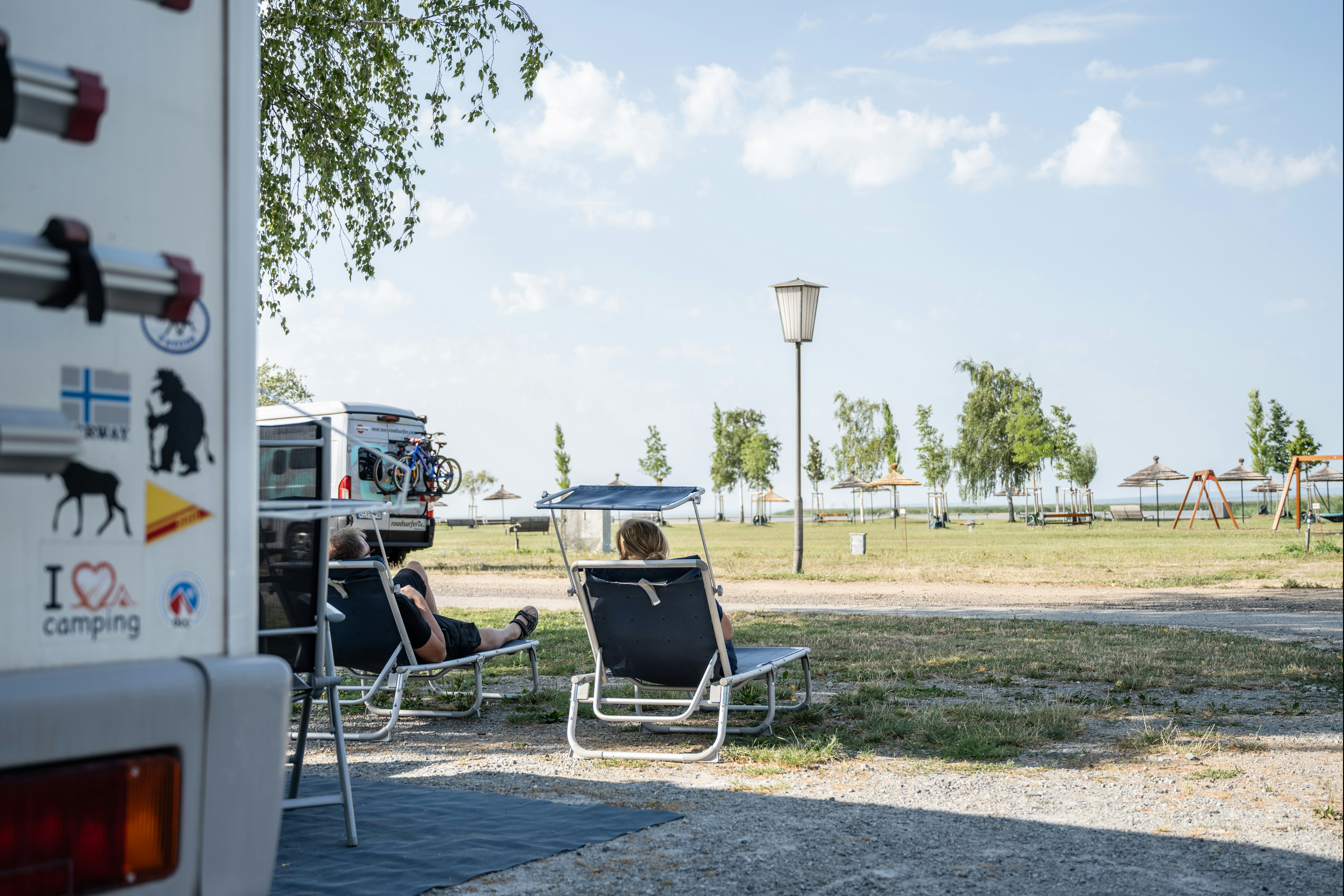 Neuer Strand Neusiedler See - Camper entspannen sich auf Liegestühlen auf ihrem Standplatz