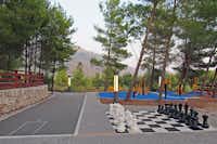 Nevio Camping -  Schachpartie und Trainingsgerät im Schatten der Baüme auf dem Campingplatz