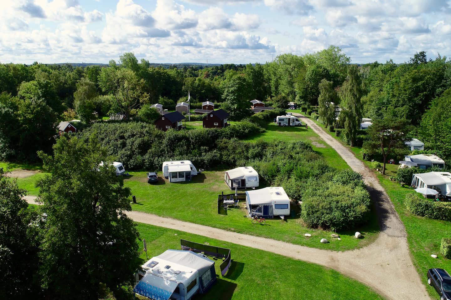 Nivå Camping - Blick auf den Wohnmobilstellplatz vom Campingplatz im Grünen zwischen Bäumen 