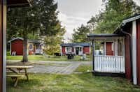 Nordic Camping Ånnaboda  -  Mobilheime vom Campingplatz mit Picknicktischen und Grills auf der Terrasse im Grünen