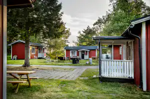 Nordic Camping Ånnaboda - Mobilheime vom Campingplatz mit Picknicktischen und Grills auf der Terrasse im Grünen