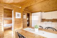 Nordic Camping Bredsand  -  Innenansicht vom Mobilheim auf dem Campingplatz mit Küche, Esstisch und Hochbetten in den Schlafbereichen