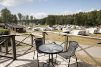 Nordic Camping Nickstabadet  - Blick von der Veranda am Mobilheim mit Esstisch auf den Wohnwagen- und Zeltstellplatz vom Campingplatz am See Nynäsviken