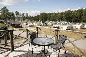 Nordic Camping Nickstabadet - Blick von der Veranda am Mobilheim mit Esstisch auf den Wohnwagen- und Zeltstellplatz vom Campingplatz am See Nynäsviken