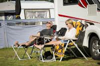 Nordic Camping Tylösand - Gäste vom Campingplatz genießen die Sonne auf dem Wohnwagenstellplatz auf grüner Wiese