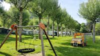 Nou Camping - Kinderspielgeräte des Campingplatzes mit Wohnwagen im Hintergrund