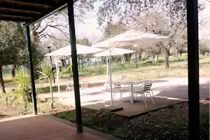 Nuraghe Ruiu - Terrasse mit Tischen, Stühlen und Sonnenschirmen auf dem Campingplatz