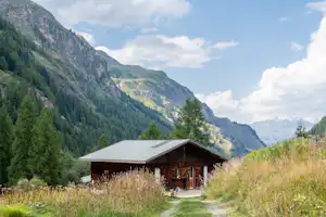 Onlycamp Camping de Tignes - Blick auf das Servicegebäude auf dem Campingplatz mit Bergen im Hintergrund