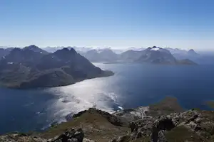 Blick von einem Berggrat auf ein weites Tal mit See, Küste und Nebel über den Bergen.