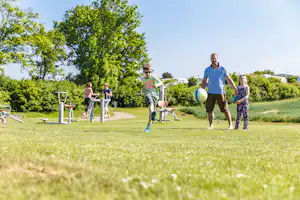 Ostsee-Campingplatz Kagelbusch - Fußball spielende Camper auf grüner Wiese vom Campingplatz, Outdoor Fitness Bereich im Hintergrund