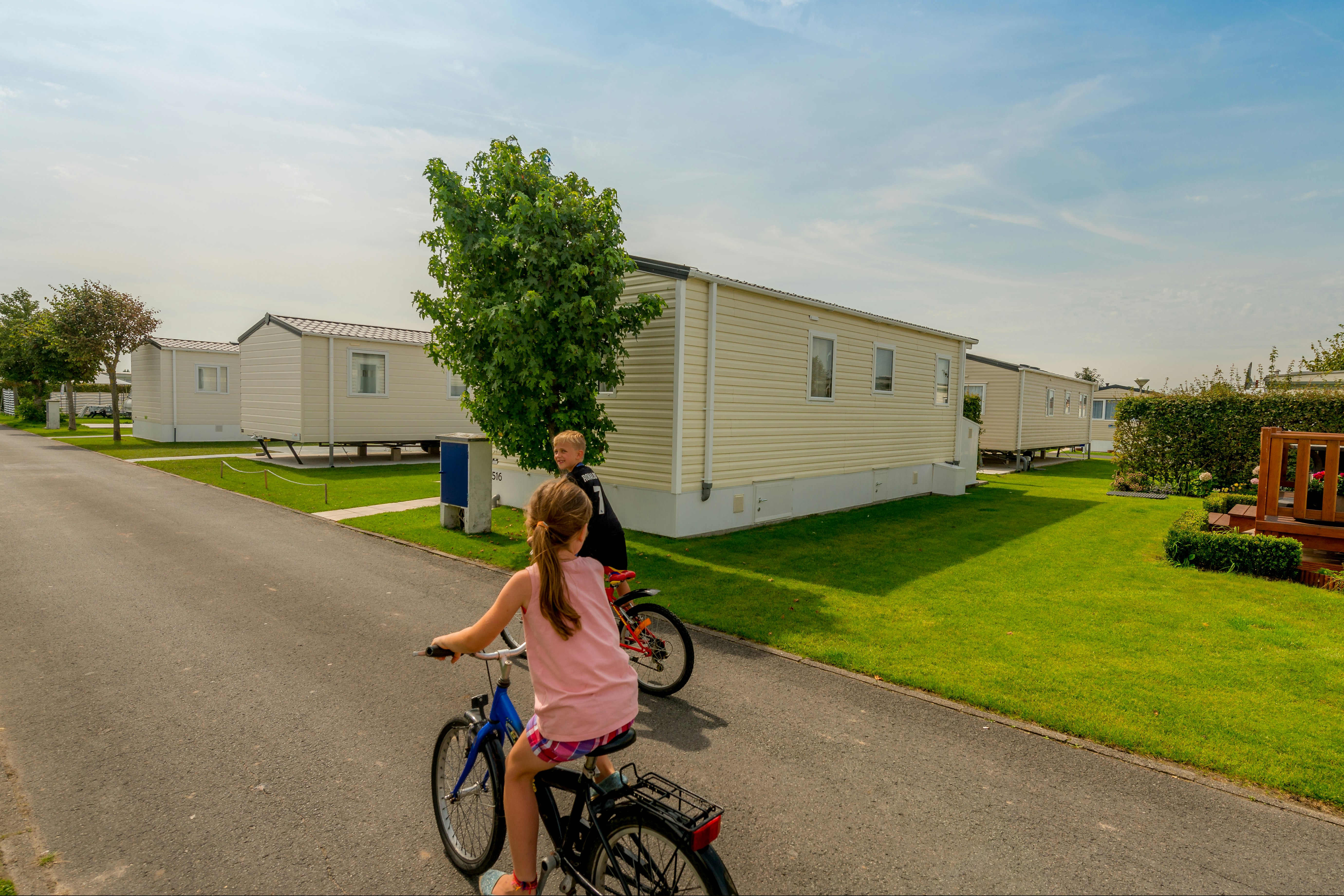 Park Merlo - Kinder fahren Fahrrad auf dem Campingplatz zwischen Mobilheimen