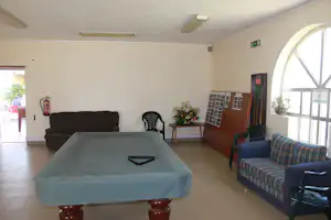 Camping-Wohnraum mit Sofa, Tisch und Stühlen, Pinnwand an der Wand und großen Fenstern im Innenbereich.