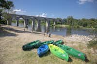 RCN-Camping La Bastide en Ardèche  - Kayaks und spazierende Camper am Fluss  am Campingplatz
