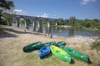 RCN-Camping La Bastide en Ardèche  - Kayaks und spazierende Camper am Fluss  am Campingplatz