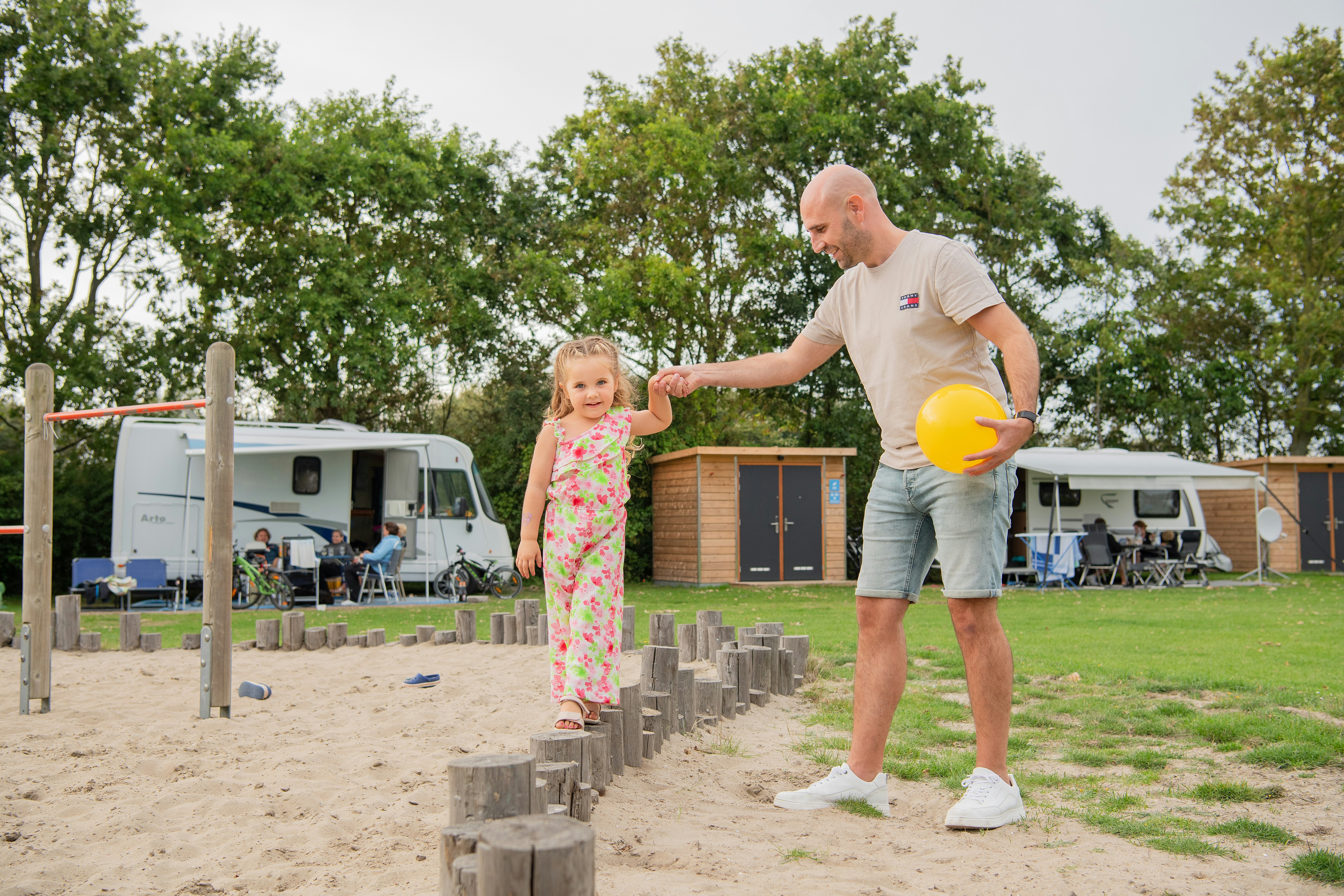 RCN Camping Toppershoedje Vater und Tochter auf dem Spielplatz und Standplätze mit Privatsanitär im Hintergund