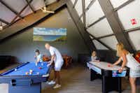 RCN Camping Zeewolde - Gemeinschaftsraum mit BIllardtisch und Airhockeytisch, an denen Camper spielen