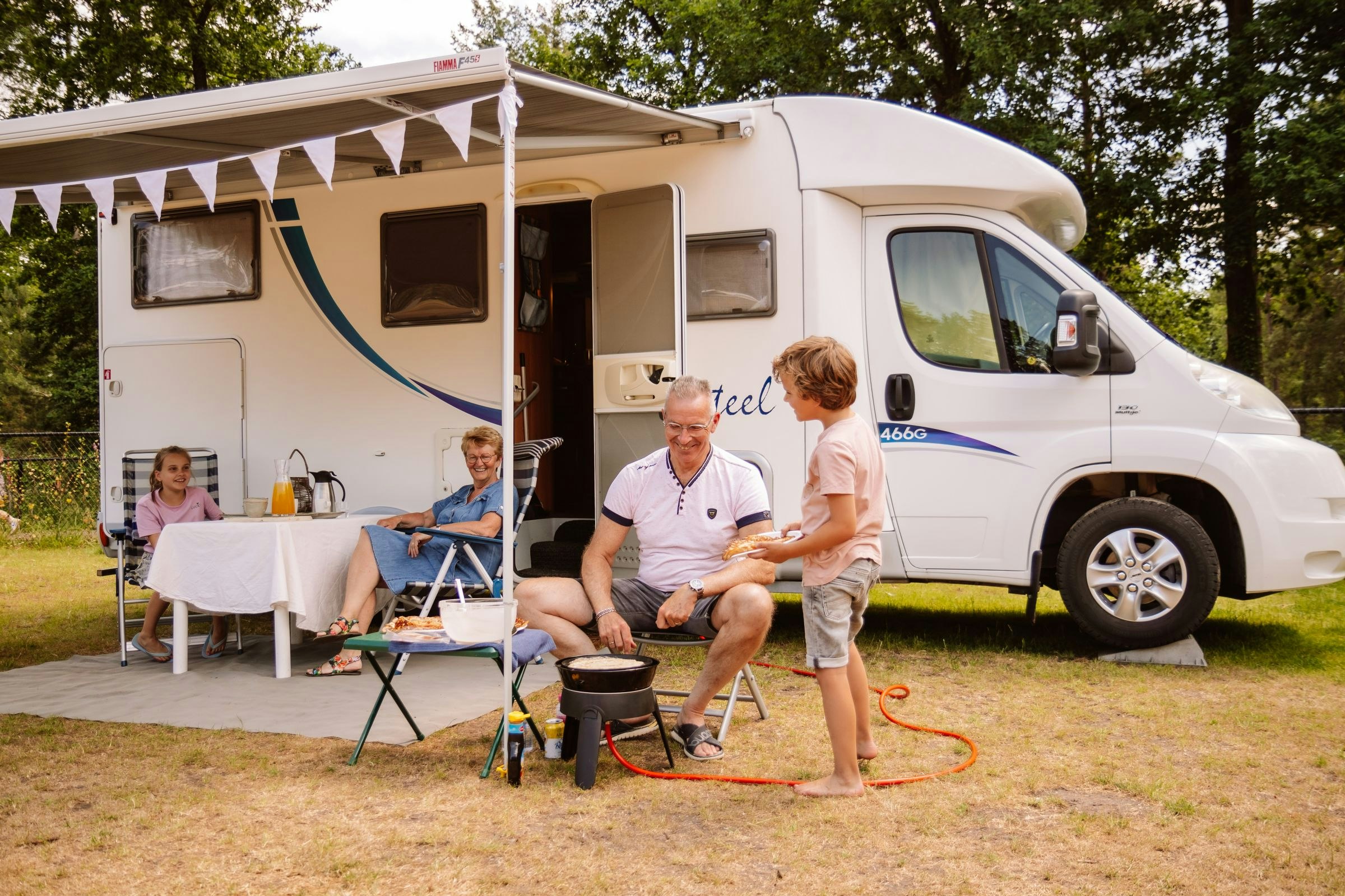 Camping Samoza - Familie sitzt vor ihrem Wohnmobil auf einem Standplatz