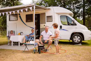 Camping Samoza - Familie sitzt vor ihrem Wohnmobil auf einem Standplatz