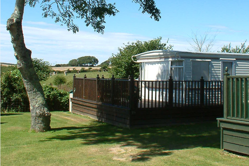 Riverside Holiday Park - Mobilheim mit Veranda und der Landschaft Cornwalls im Hintergrund