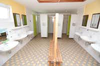 Rosen-Camp Kniese - Innenraum des Sanitärgebäudes mit Waschbecken und Duschkabinen
