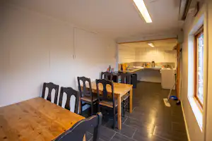 Gemeinschaftsraum im Campinghaus mit Esstisch, Stühlen und Blick in die Küche mit Arbeitsfläche und Schränken.