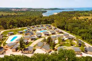 Luftaufnahme eines Campingplatzes mit mehreren Ferienhäusern, Pool und Wegen im Grünen am See.