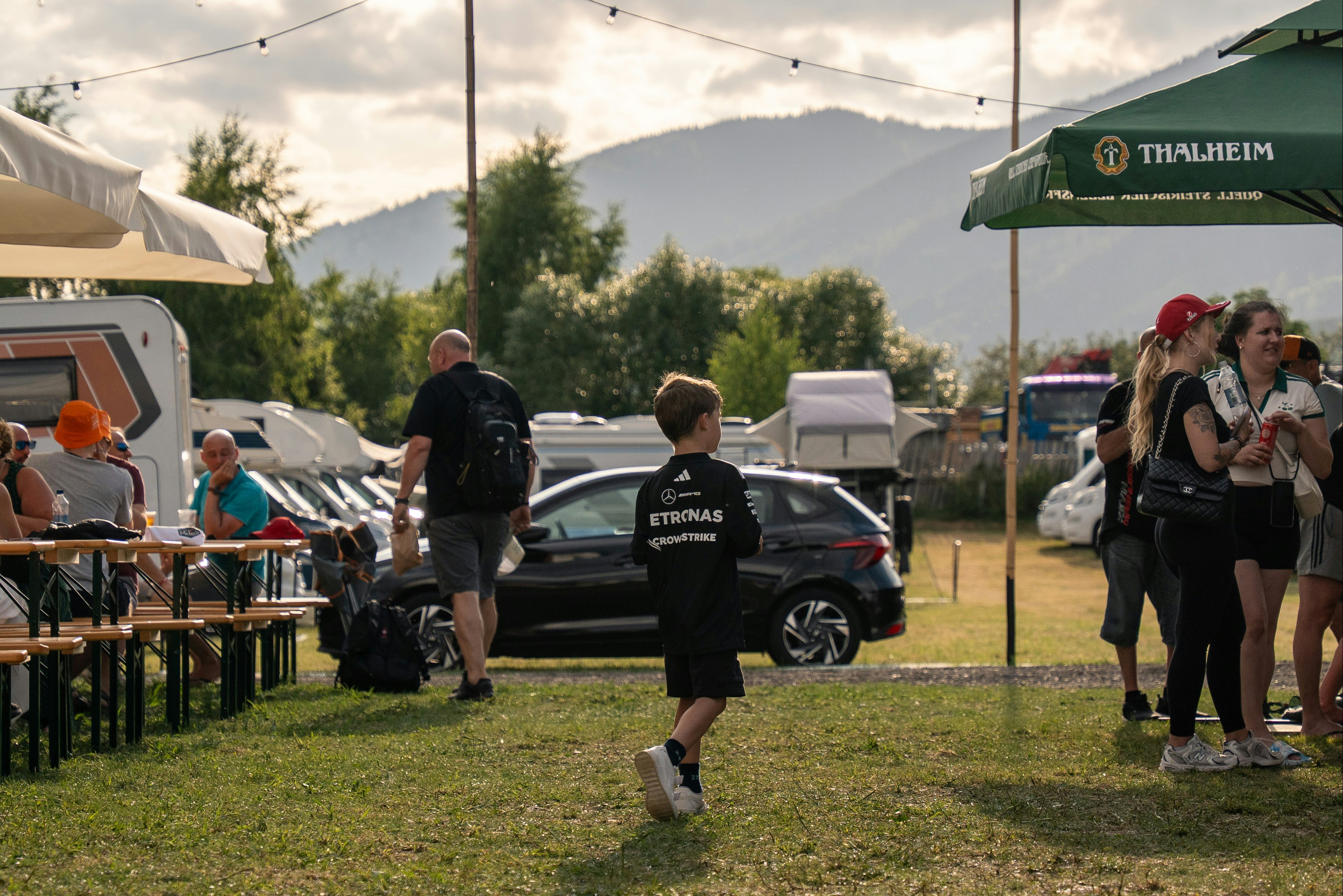 Schitterhof Camping - Camper sitzen zusammen auf Bierbänken auf der Standplatzwiese