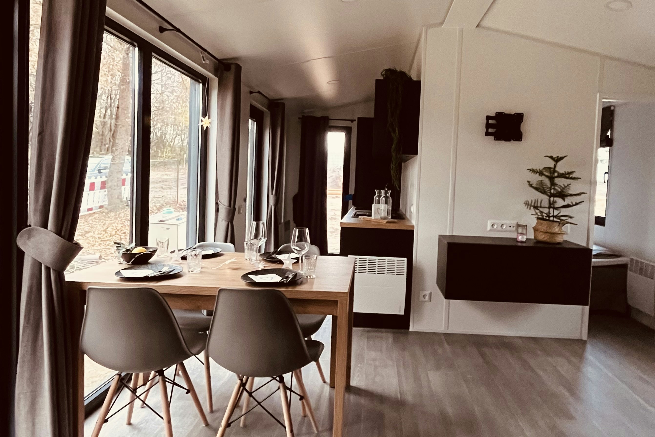 Essbereich in einem Mobilhome: Holztisch mit Stühlen, große Fensterfront und Blick auf die Terrasse.