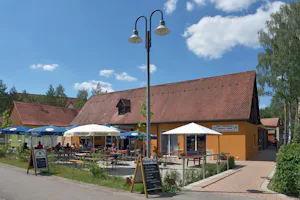 Seecamping Langlau - Biergarten mit Sonnenschirmen und Supermarkt auf dem Campingplatz