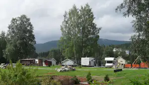 Von Bäumen umringte Wohnwagen- und Wohnmobilstellplätze auf der Wiese des Campingplatzes Sølvgarden Feriesenter