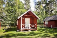 Nordic Camping Stensö  -  Mobilheime vom Campingplatz mit Veranden und Picknicktischen auf grüner Wiese